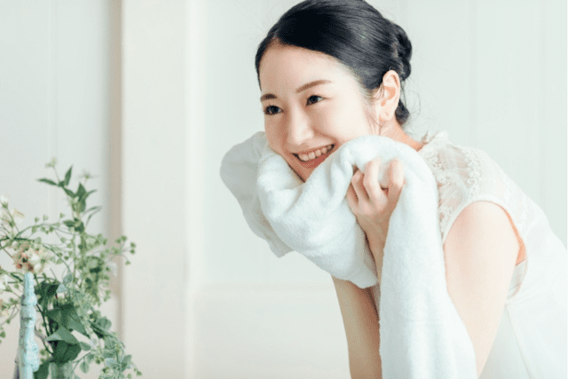 クレンジングと洗顔でメイクと汚れを落とした後、心地よい洗い上がりに満足し、柔らかいタオルで顔を拭く女性の様子