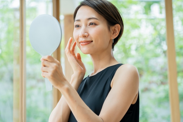 手鏡でお肌の状態を確認し、春のUVケアや丁寧な保湿による仕上がりに満足している女性の様子