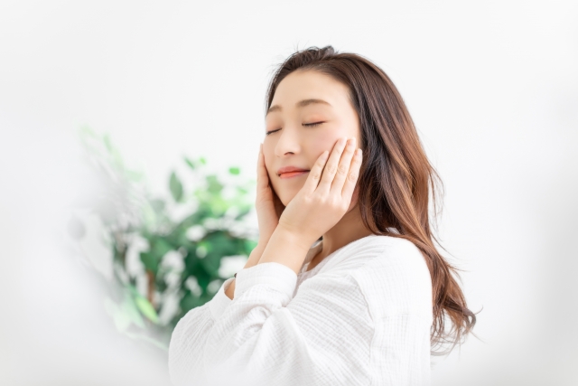 両手で優しく頬を包み込み、心地よいスキンケアの時間に安らぎを感じて目を閉じている女性の様子|アーバンコスメ