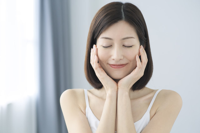 丁寧なハンドプレスで美容液をお肌になじませ、ふっくらとした潤いの手応えに満足した表情を見せる女性の様子｜アーバンコスメ
