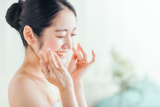 美容液のなじみの良さを実感し、心身ともにリラックスして、笑顔でハンドプレスを続ける女性の様子｜アーバンコスメ