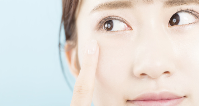 ふと鏡を見たときに気づいたまぶたのゆるみやクマ、乾燥など、目もとまわりのサインを指先で優しく確認している女性の様子｜アーバンコスメ